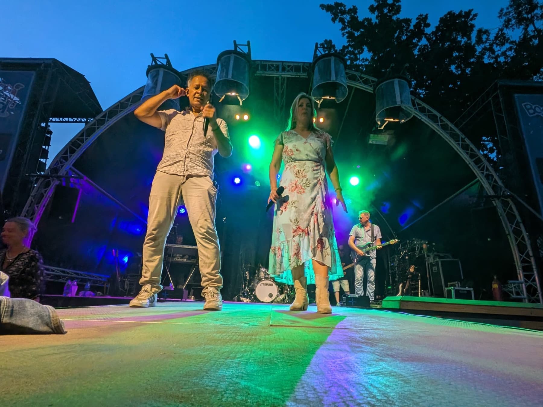De zanger en zangeres dansen op het podium in groen en blauw licht
