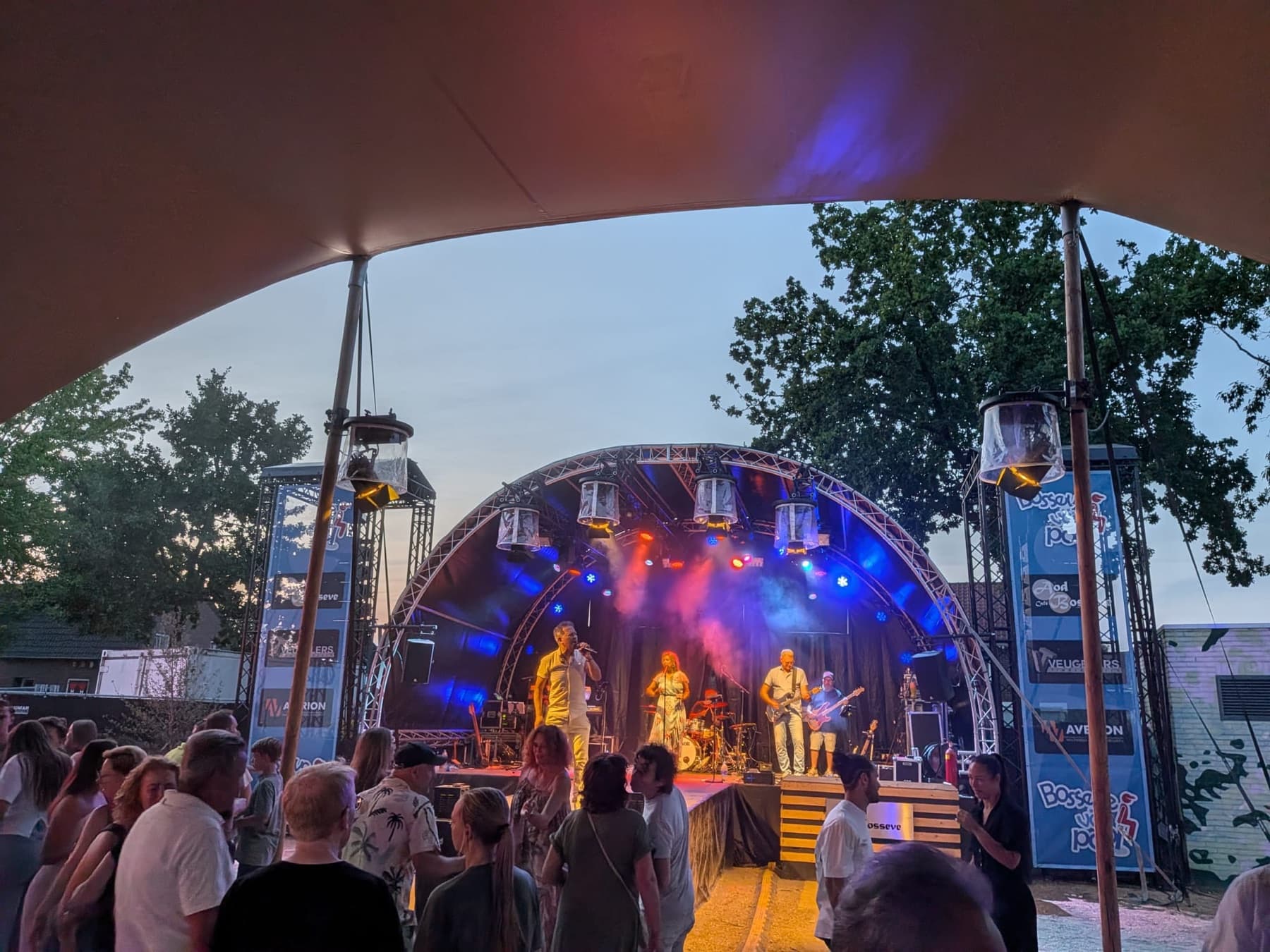 Het verlichte festivalpodium in de avond met publiek op de voorgrond